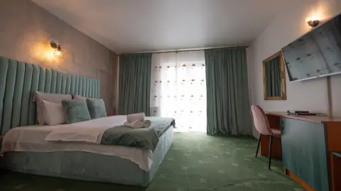 Double bedroom with green carpet and balcony access