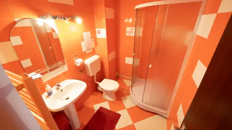 Orange-toned bathroom with shower, basin and toilet