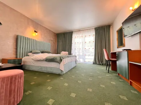 Double bedroom with green carpet, armchair and balcony