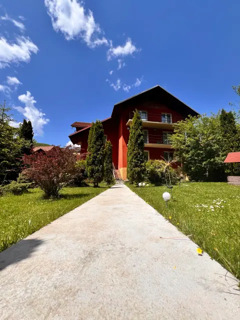 Garden path towards the red guesthouse facade