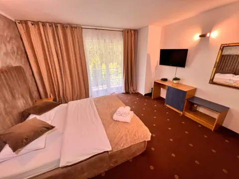 Double bed and balcony in the brown-carpeted room