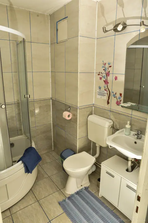 Bathroom with shower, white furniture and blue bath mat