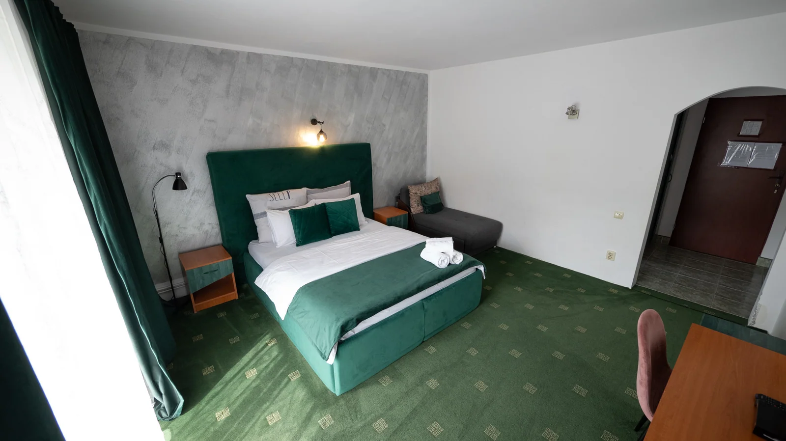 Cameră cu pat dublu verde și dulap lângă intrare